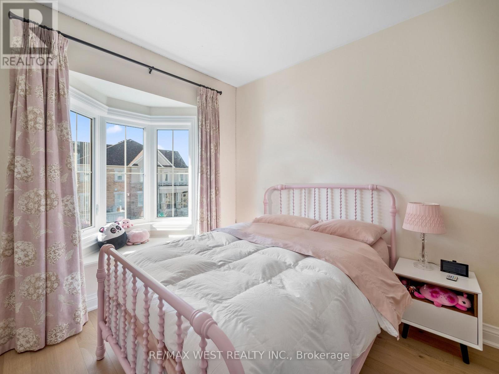 A bedroom with a pink bed and a window with curtains.