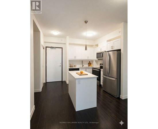 A kitchen with white cabinets and a refrigerator.