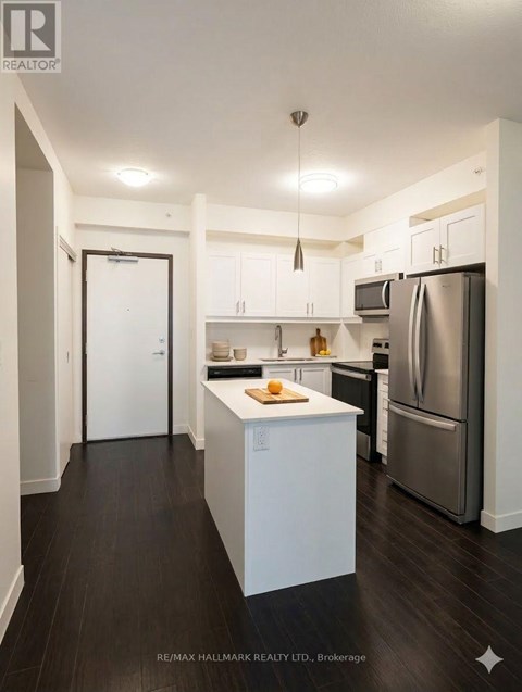 A kitchen with white cabinets and a refrigerator.