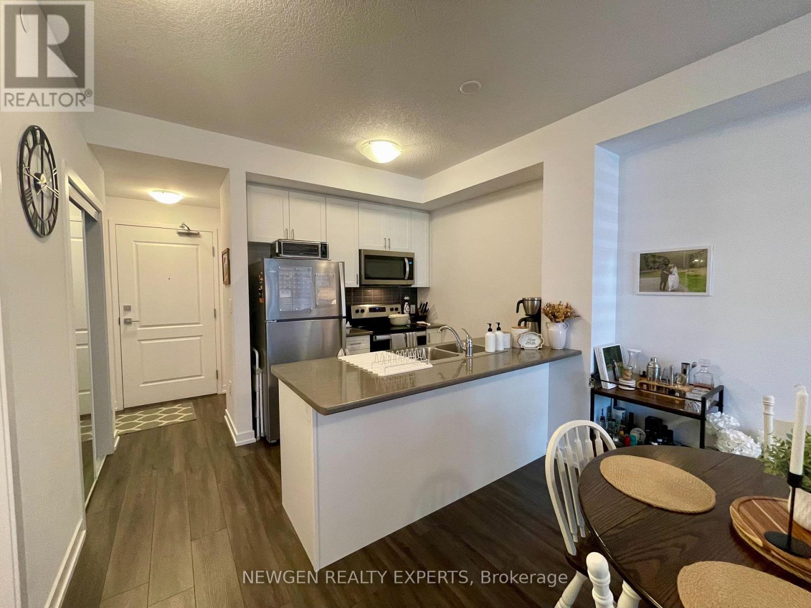 A kitchen with a table and chairs in the foreground and a refrigerator, microwave, and oven in the background.