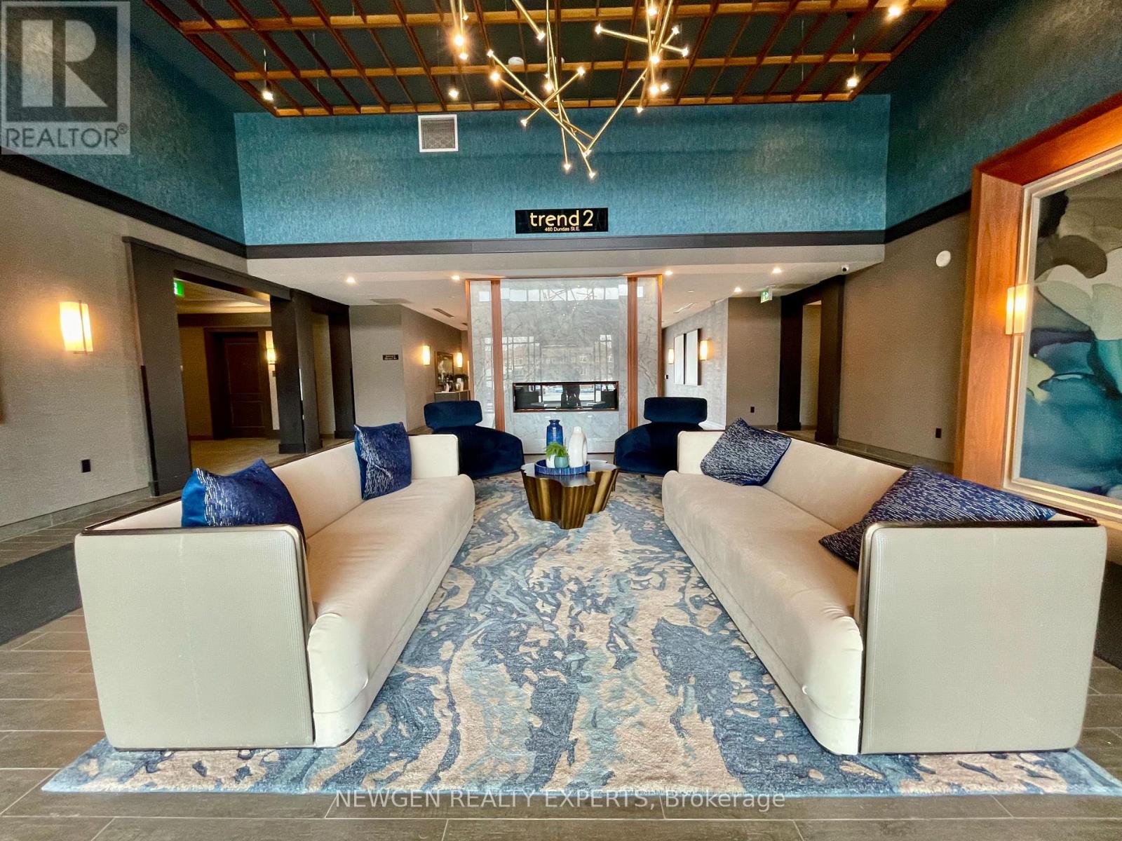 A living room with a long white couch and a blue rug.