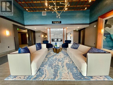 A living room with a long white couch and a blue rug.