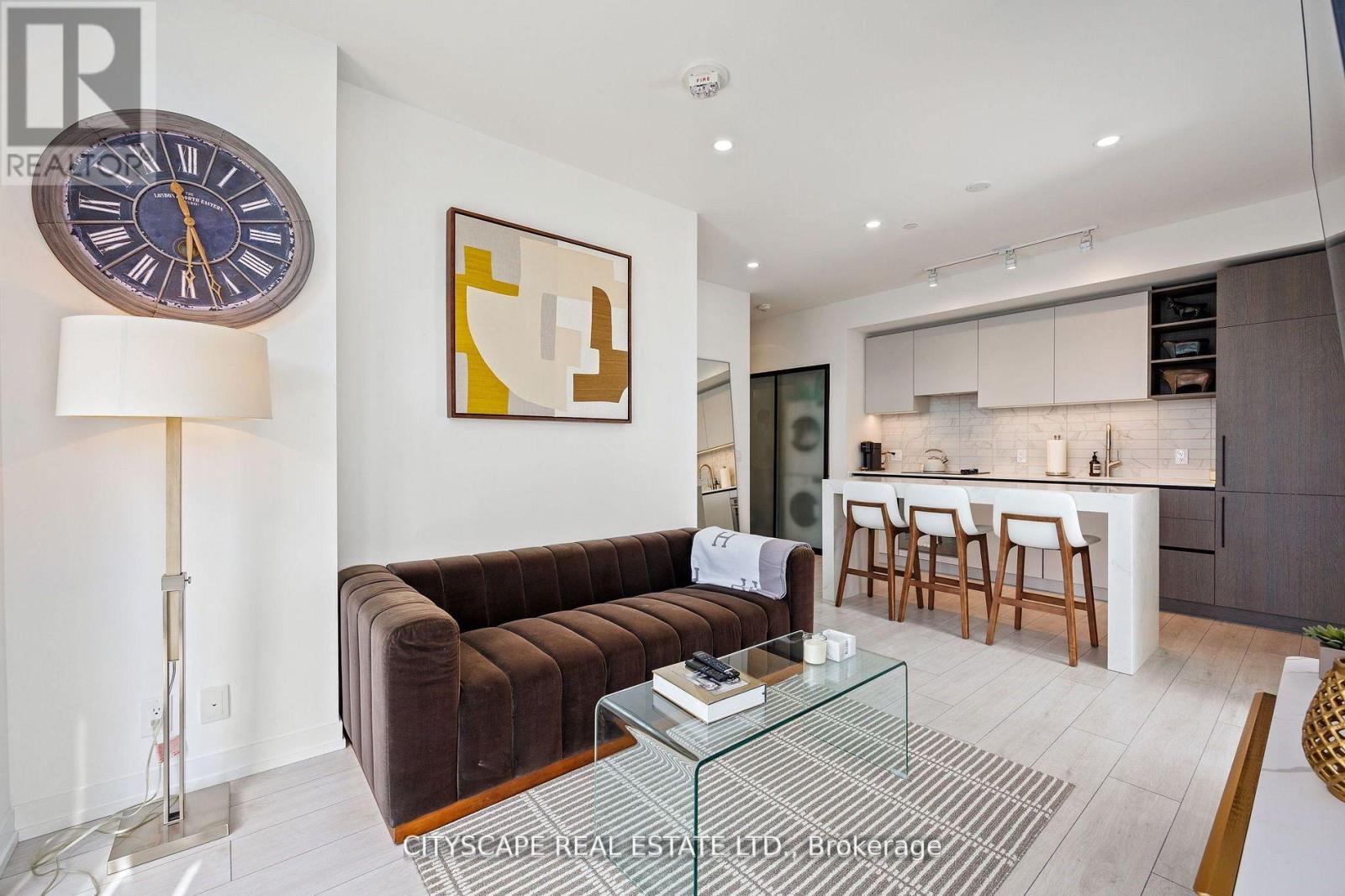 A living room with a brown couch and a glass coffee table.