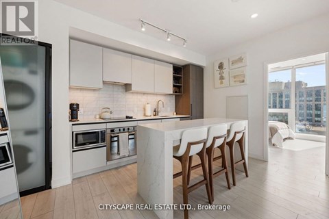 A modern kitchen with white cabinets and a marble island.
