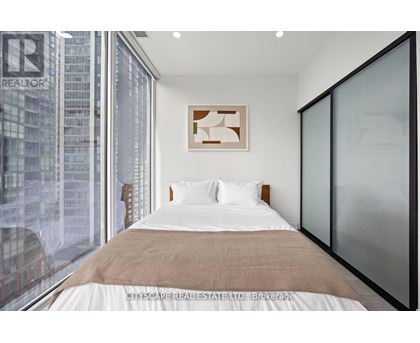 A bedroom with a large bed and a window overlooking a cityscape.