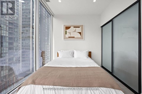 A bedroom with a large bed and a window overlooking a cityscape.
