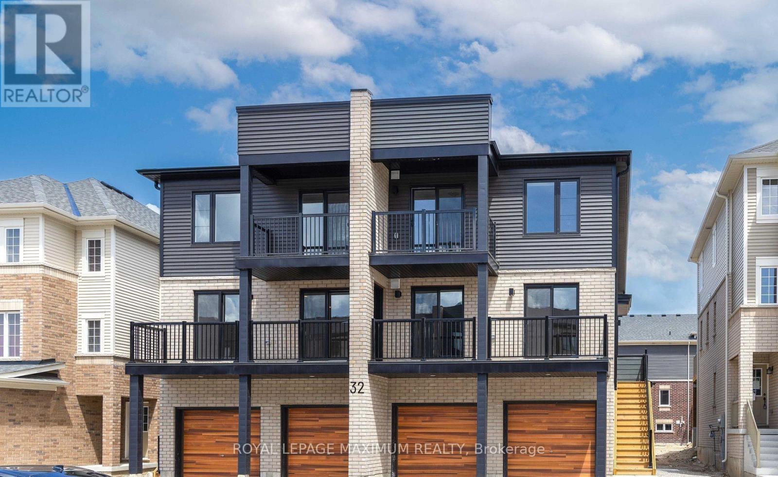 A modern two-story house with a balcony and garage doors.