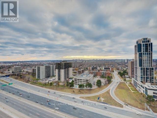 A cityscape with a highway and buildings under a cloudy sky.