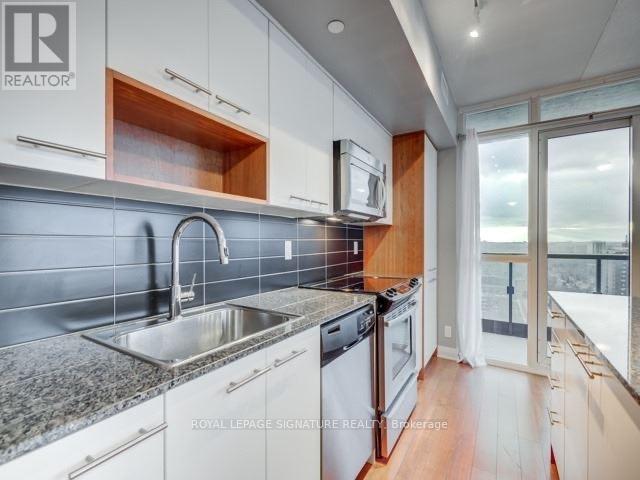 A modern kitchen with white cabinets and a stainless steel sink.