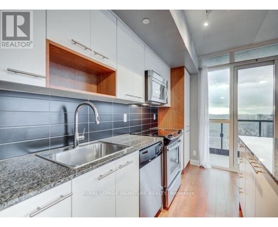A modern kitchen with white cabinets and a stainless steel sink.