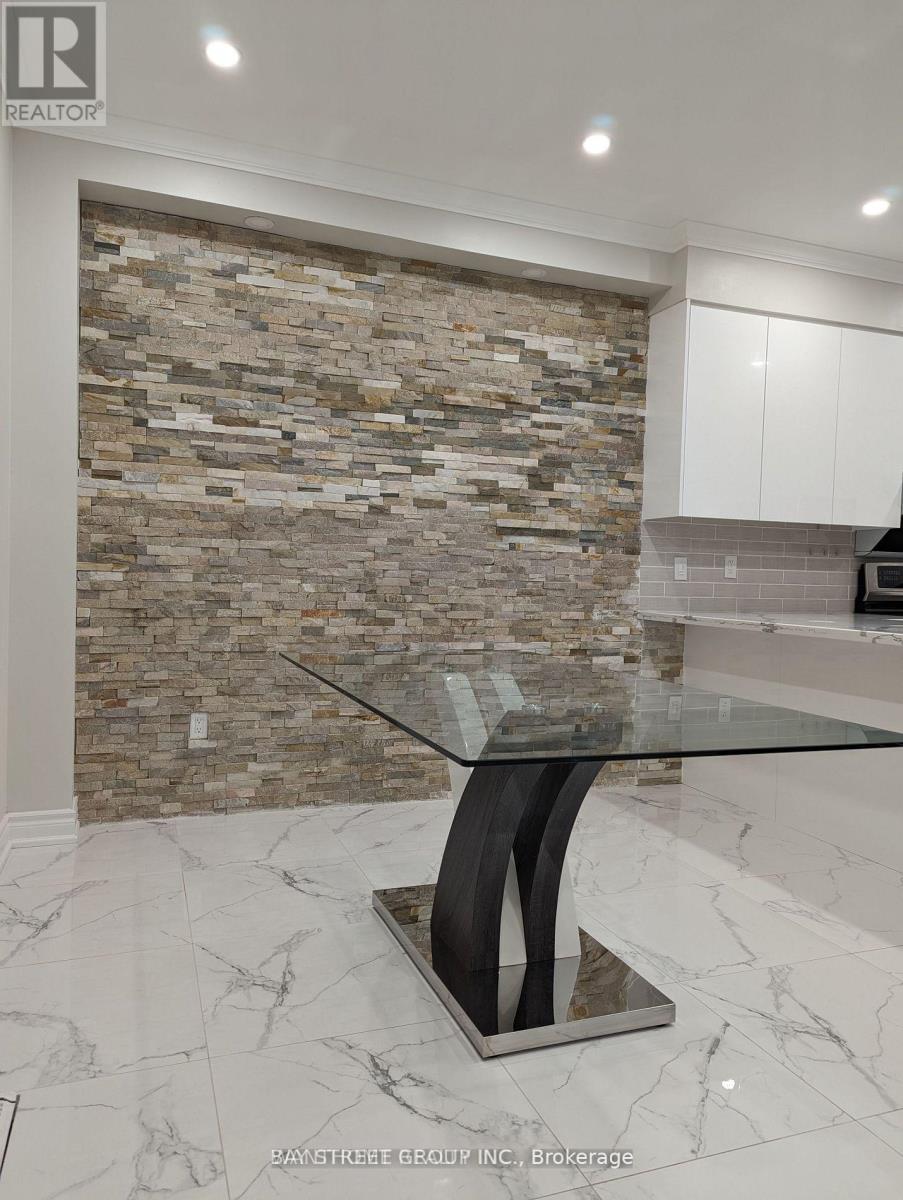A modern kitchen with a glass table and a stone wall.