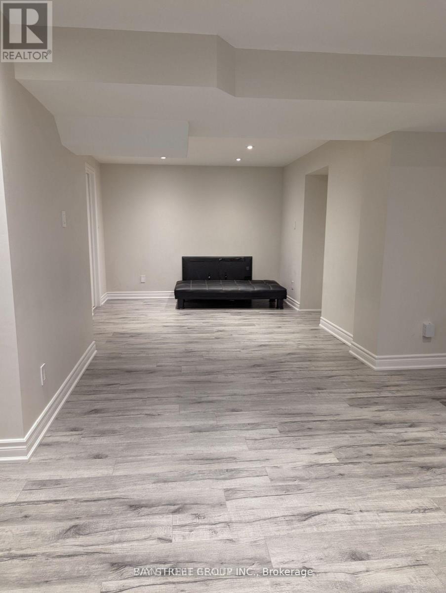 A spacious room with a black couch and wooden flooring.