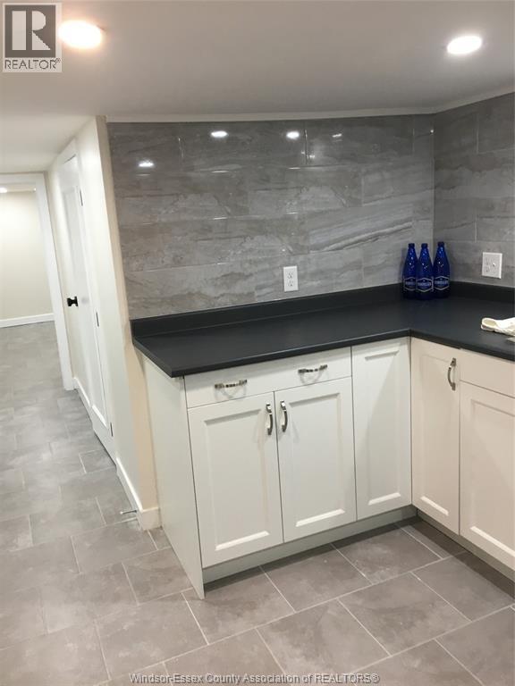 A kitchen with white cabinets and a black countertop.