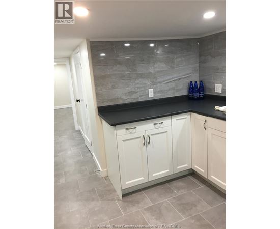 A kitchen with white cabinets and a black countertop.