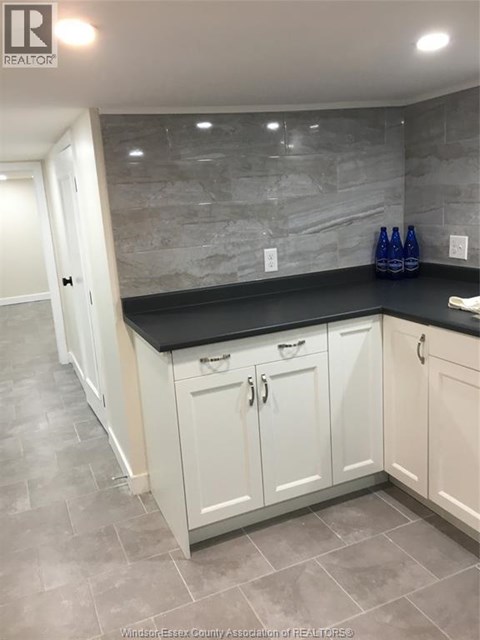 A kitchen with white cabinets and a black countertop.