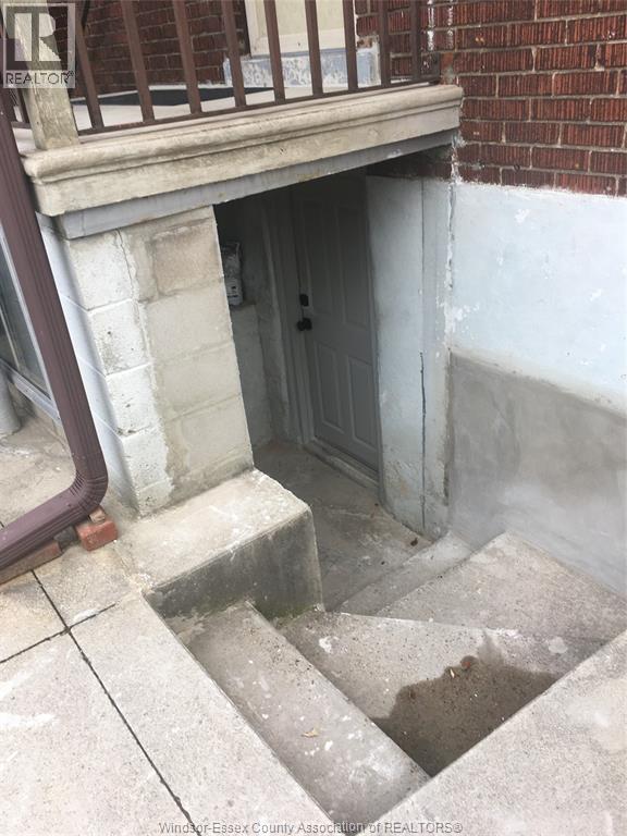 A doorway in a building with a brick wall and a concrete floor.