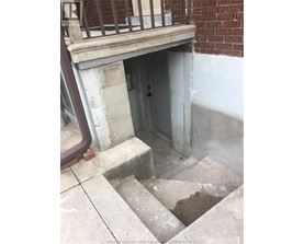 A doorway in a building with a brick wall and a concrete floor.
