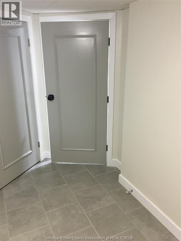 A white door is in a hallway with a tiled floor.