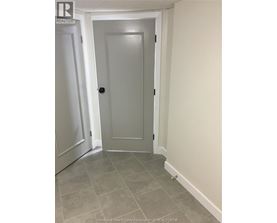 A white door is in a hallway with a tiled floor.