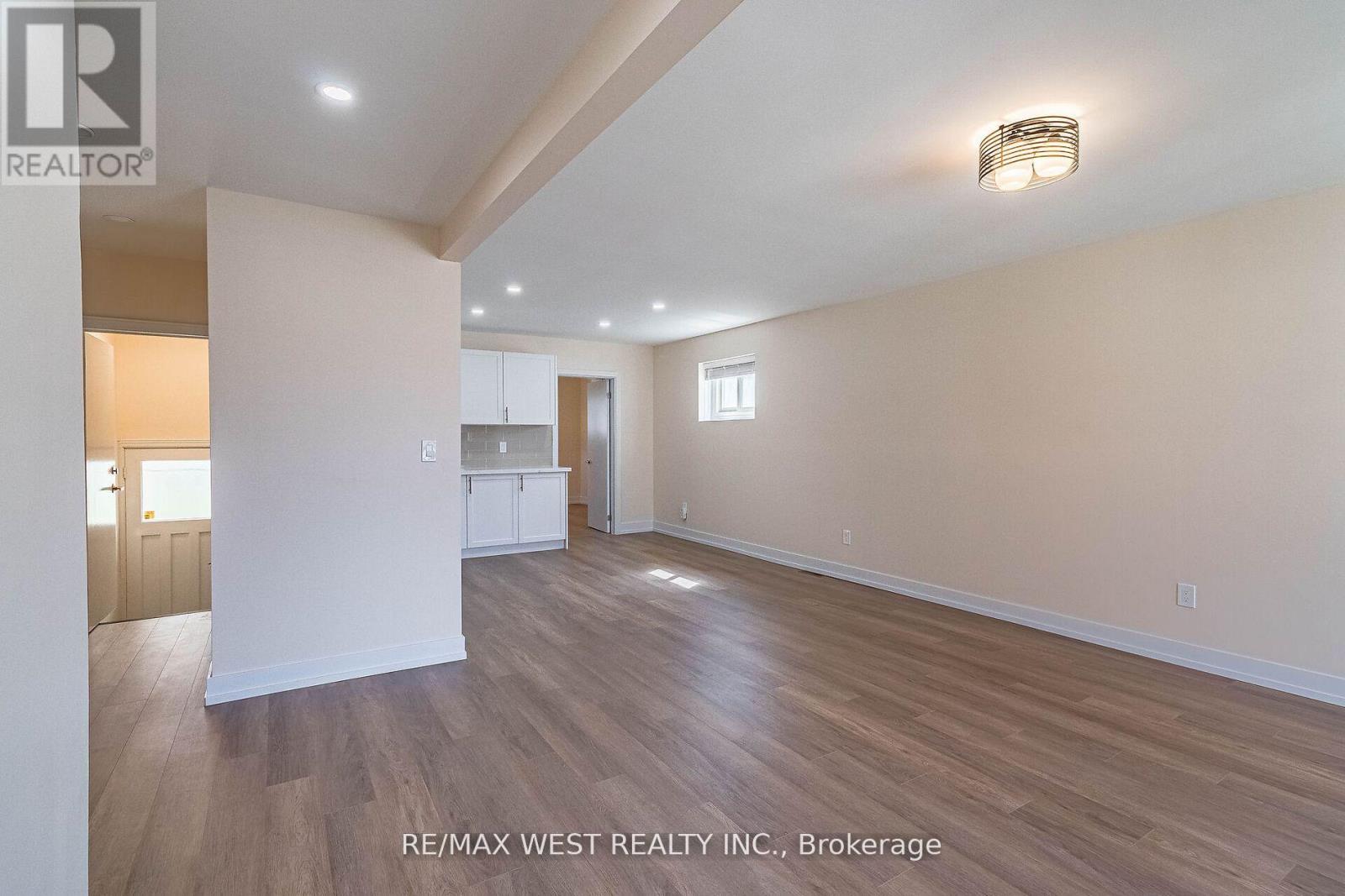 A spacious room with wooden flooring and white walls, with a light on the ceiling.