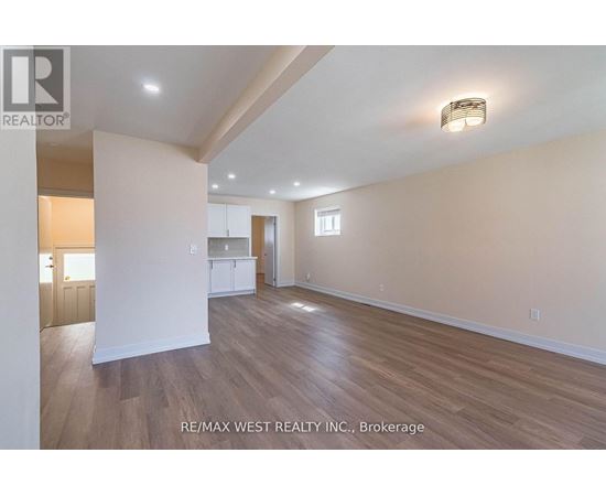 A spacious room with wooden flooring and white walls, with a light on the ceiling.