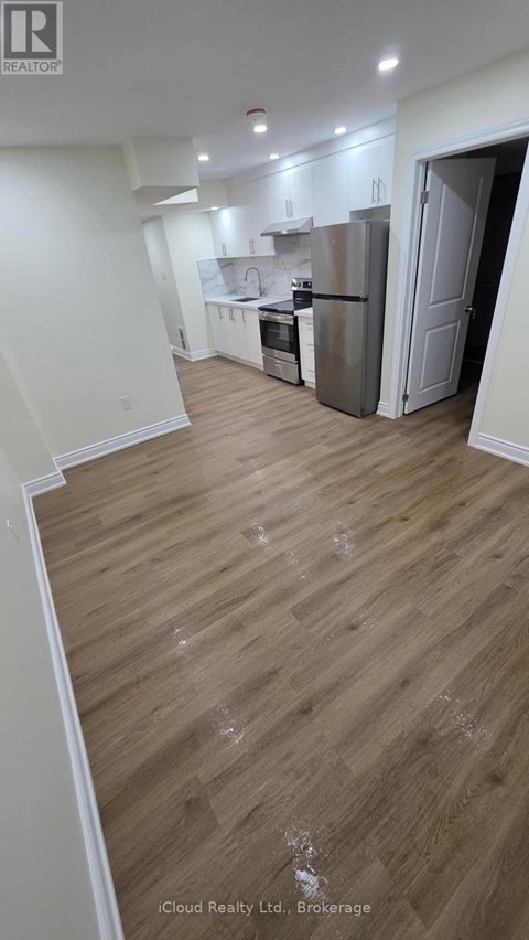 A kitchen with a refrigerator and wooden floors.