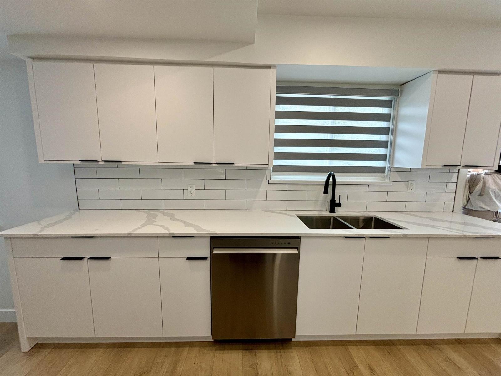 A kitchen with white cabinets and a stainless steel dishwasher.