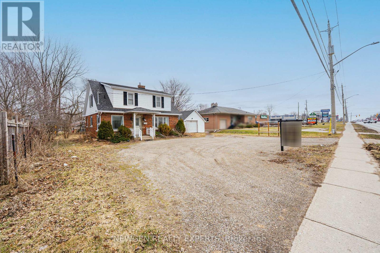 A realtor photo of a house with a gravel driveway and a sidewalk.