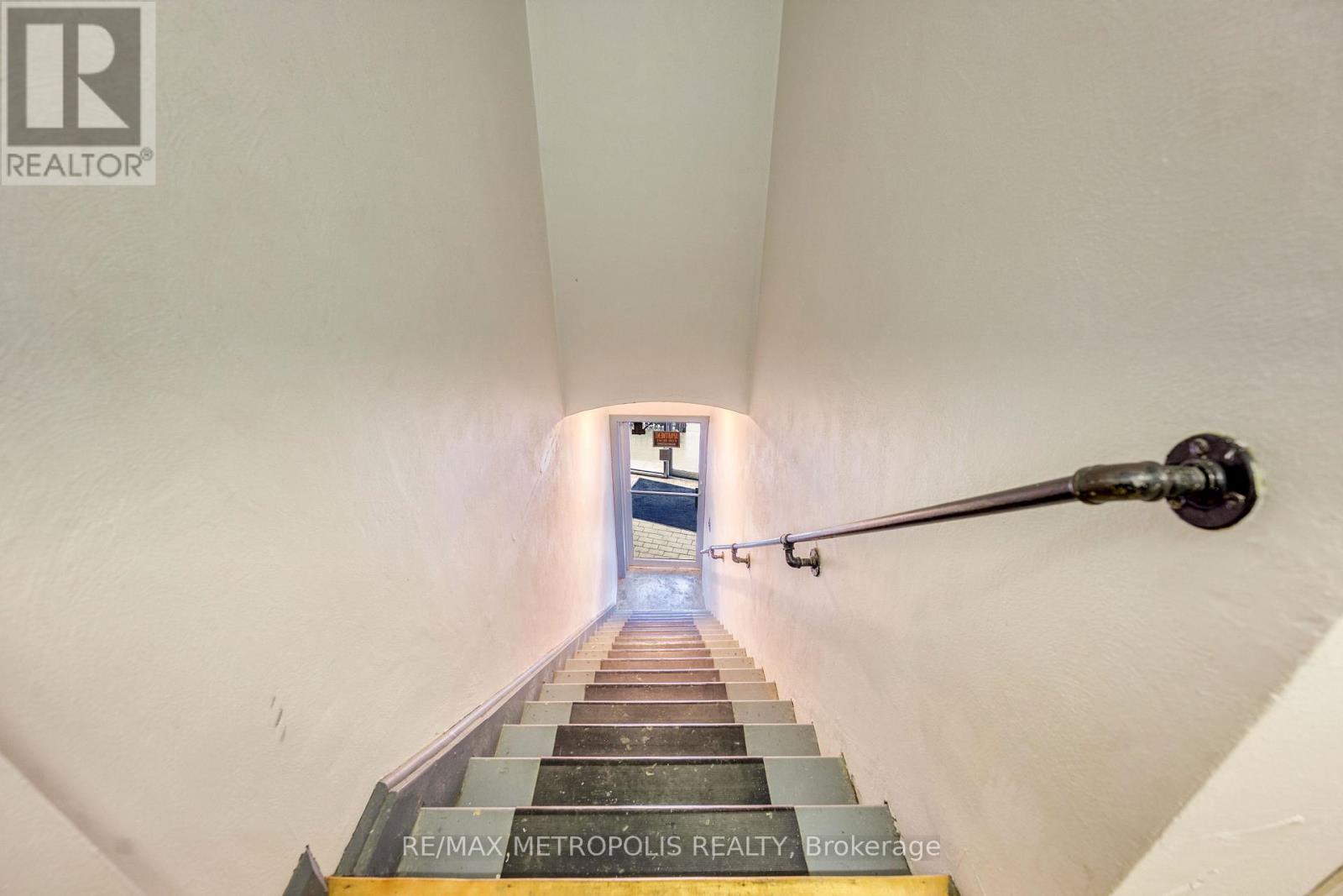 A staircase with a metal handrail leading to a door at the end.