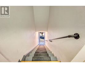 A staircase with a metal handrail leading to a door at the end.