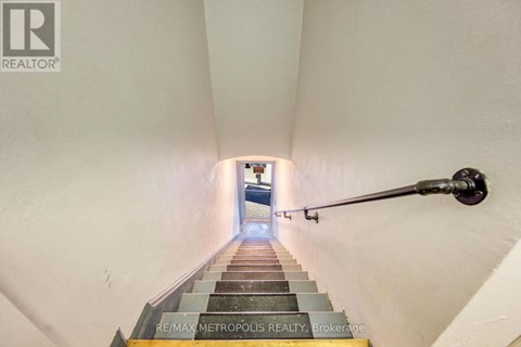 A staircase with a metal handrail leading to a door at the end.