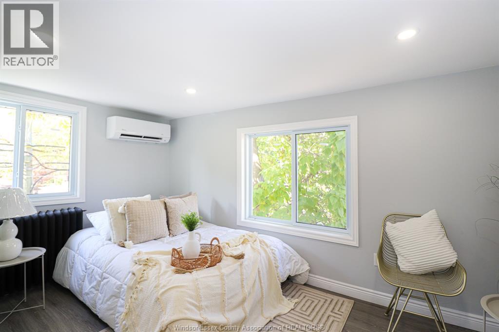 A bedroom with a bed, chair, and window.