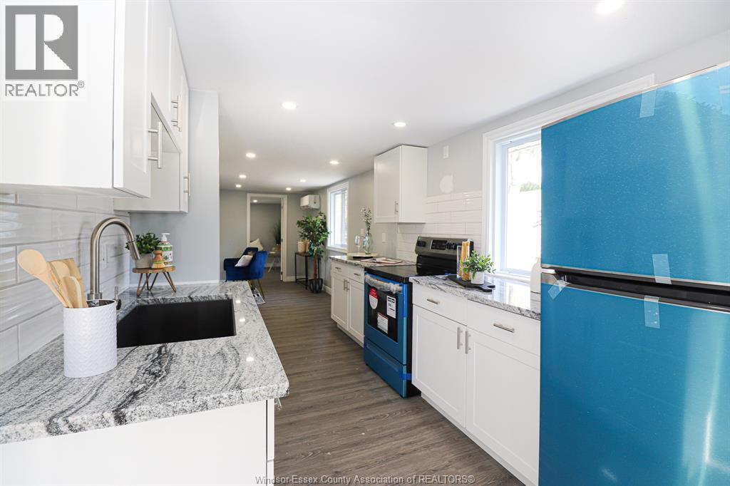 A kitchen with a blue refrigerator and white cabinets.