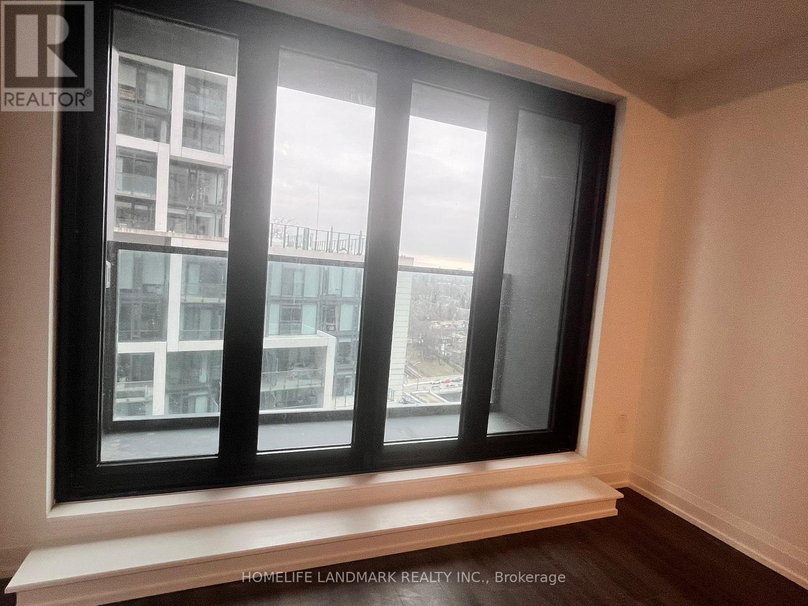 A window with a view of a cityscape and a building across the street.