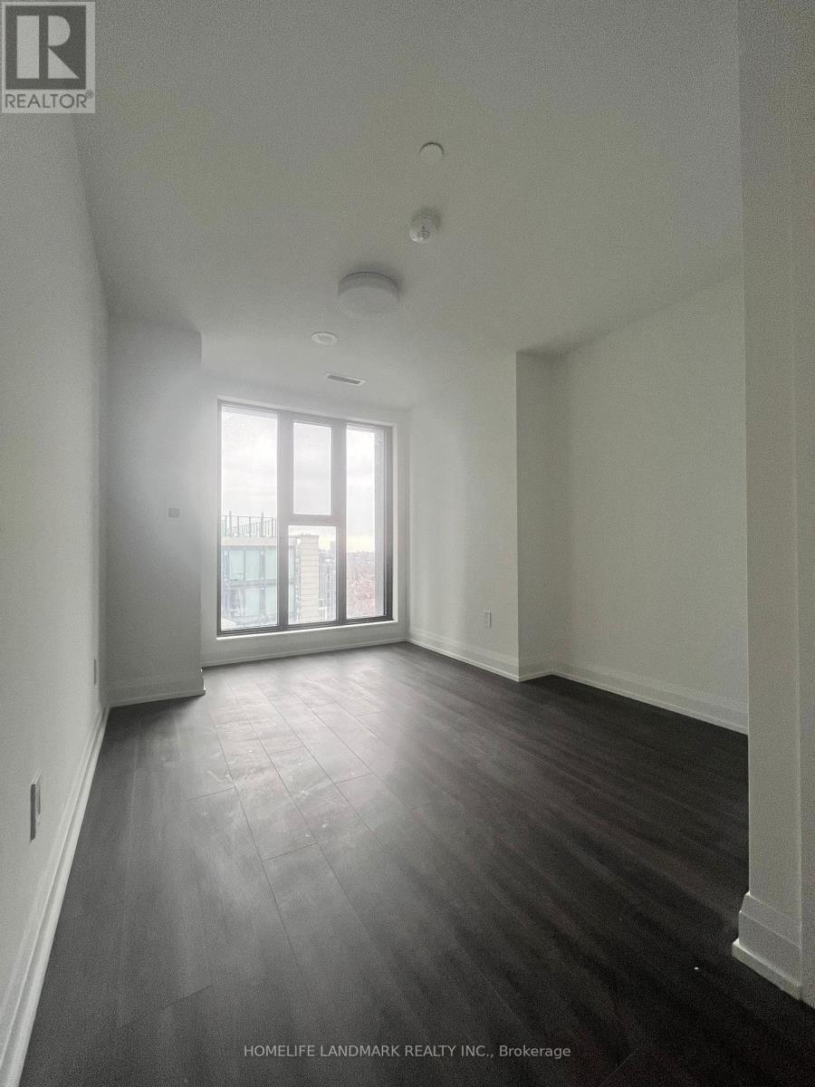 A spacious room with wooden floors and a large window.