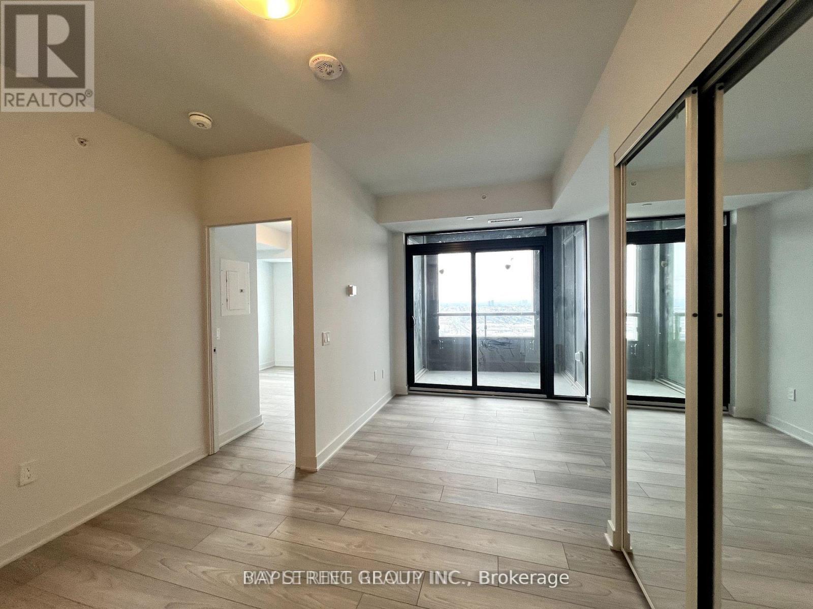 A spacious room with a sliding glass door leading to a balcony.