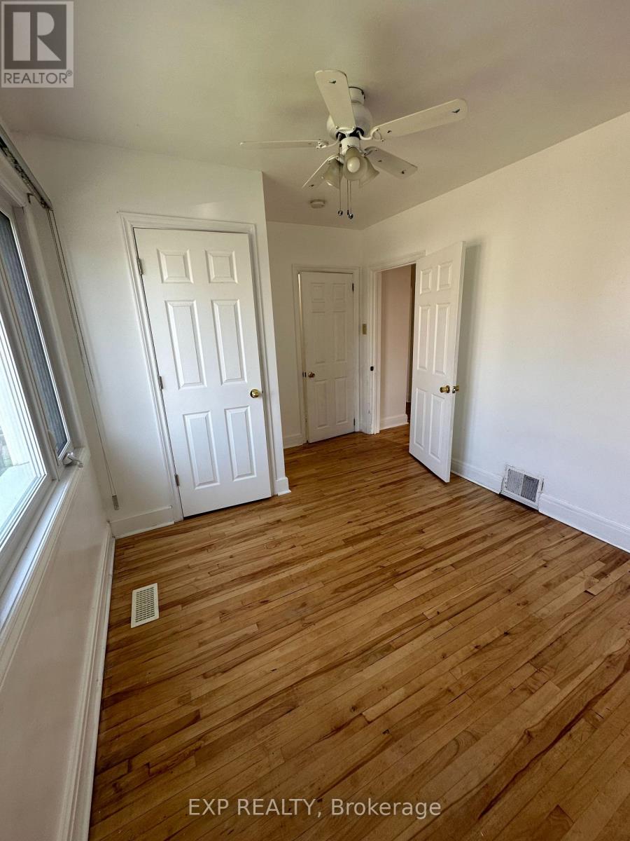 A room with wooden flooring and a window overlooking a house.