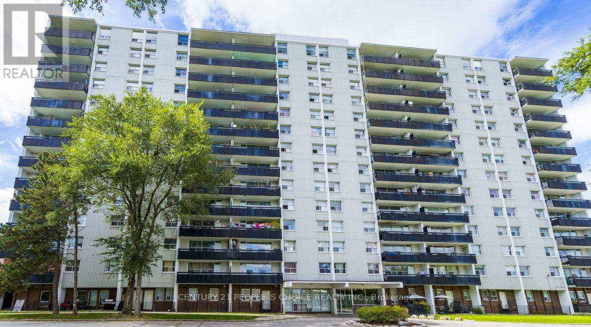 A large white apartment building with balconies and a green lawn in front.
