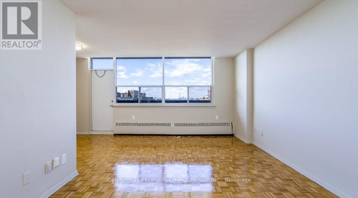 A large empty room with a window overlooking a cityscape.