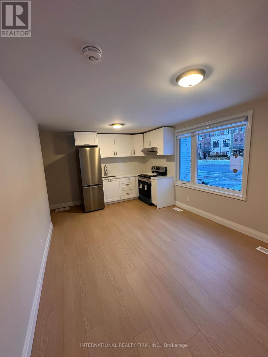 A kitchen area with a refrigerator, dishwasher, and a window overlooking a pool.