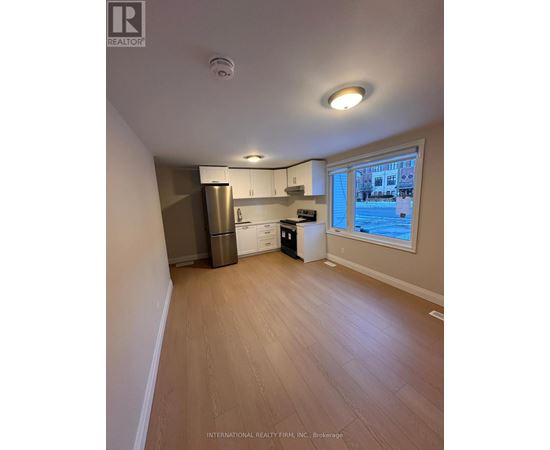 A kitchen area with a refrigerator, dishwasher, and a window overlooking a pool.