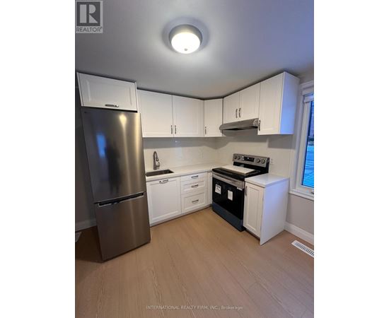 A kitchen with white cabinets and a stainless steel refrigerator.