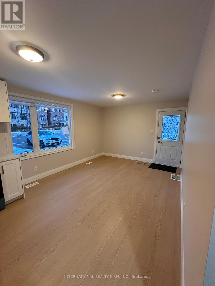 A room with wooden flooring and a window showing a street view.