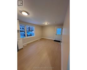 A room with wooden flooring and a window showing a street view.