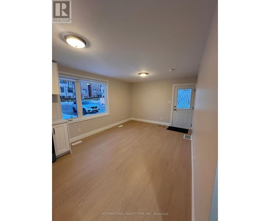 A room with wooden flooring and a window showing a street view.