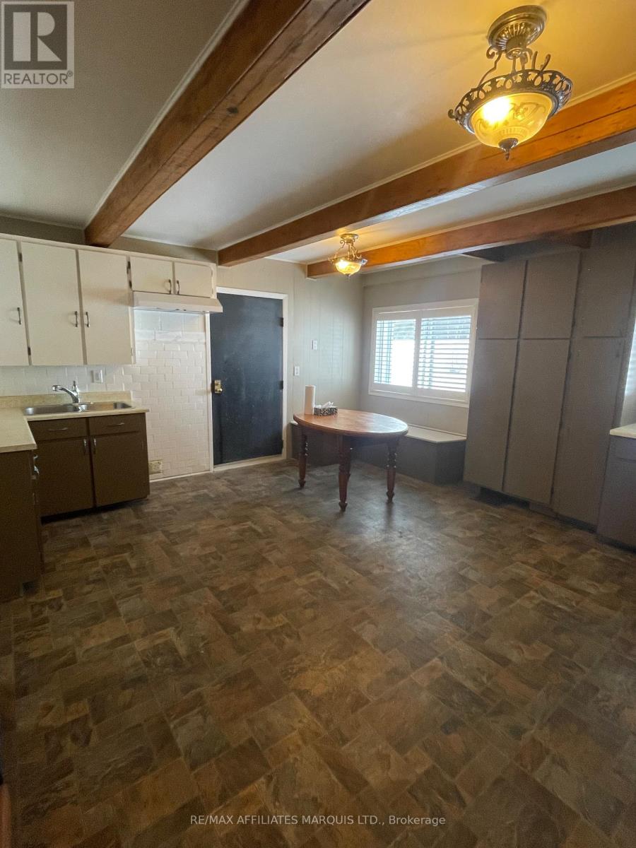 A kitchen with wooden flooring and a person standing by the window.