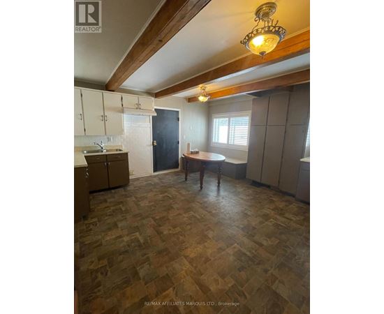 A kitchen with wooden flooring and a person standing by the window.