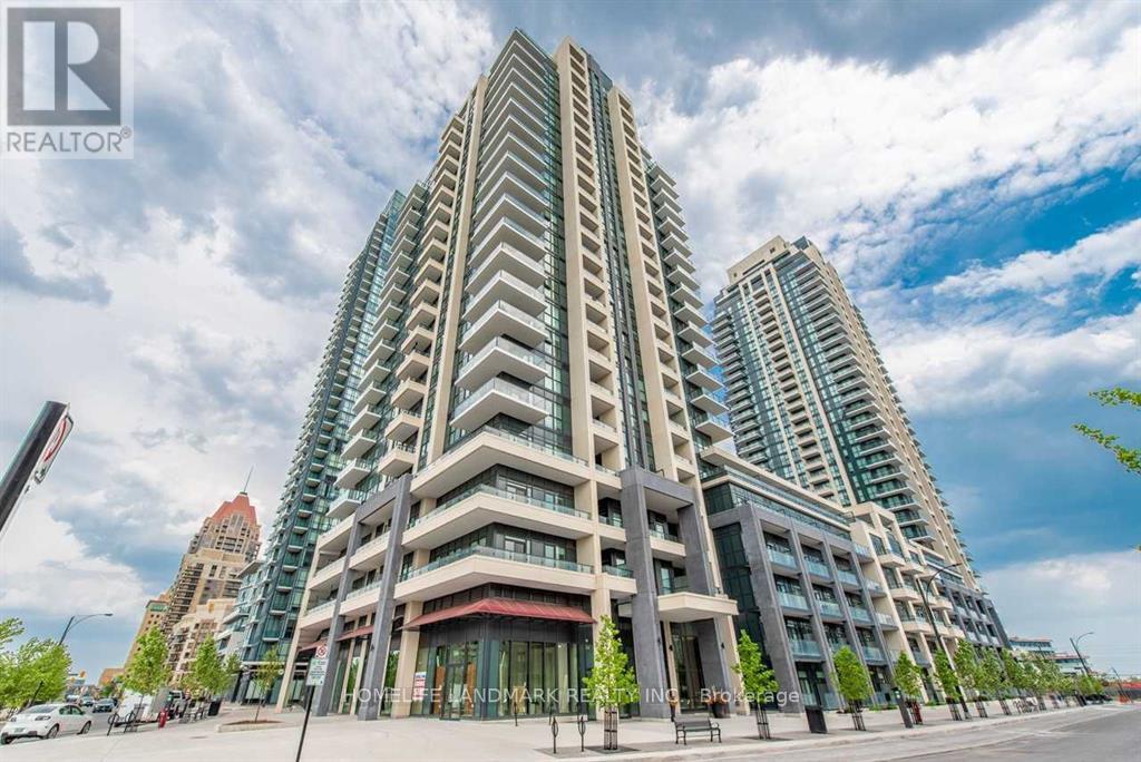A tall residential building with a glass facade stands in front of a cloudy sky.