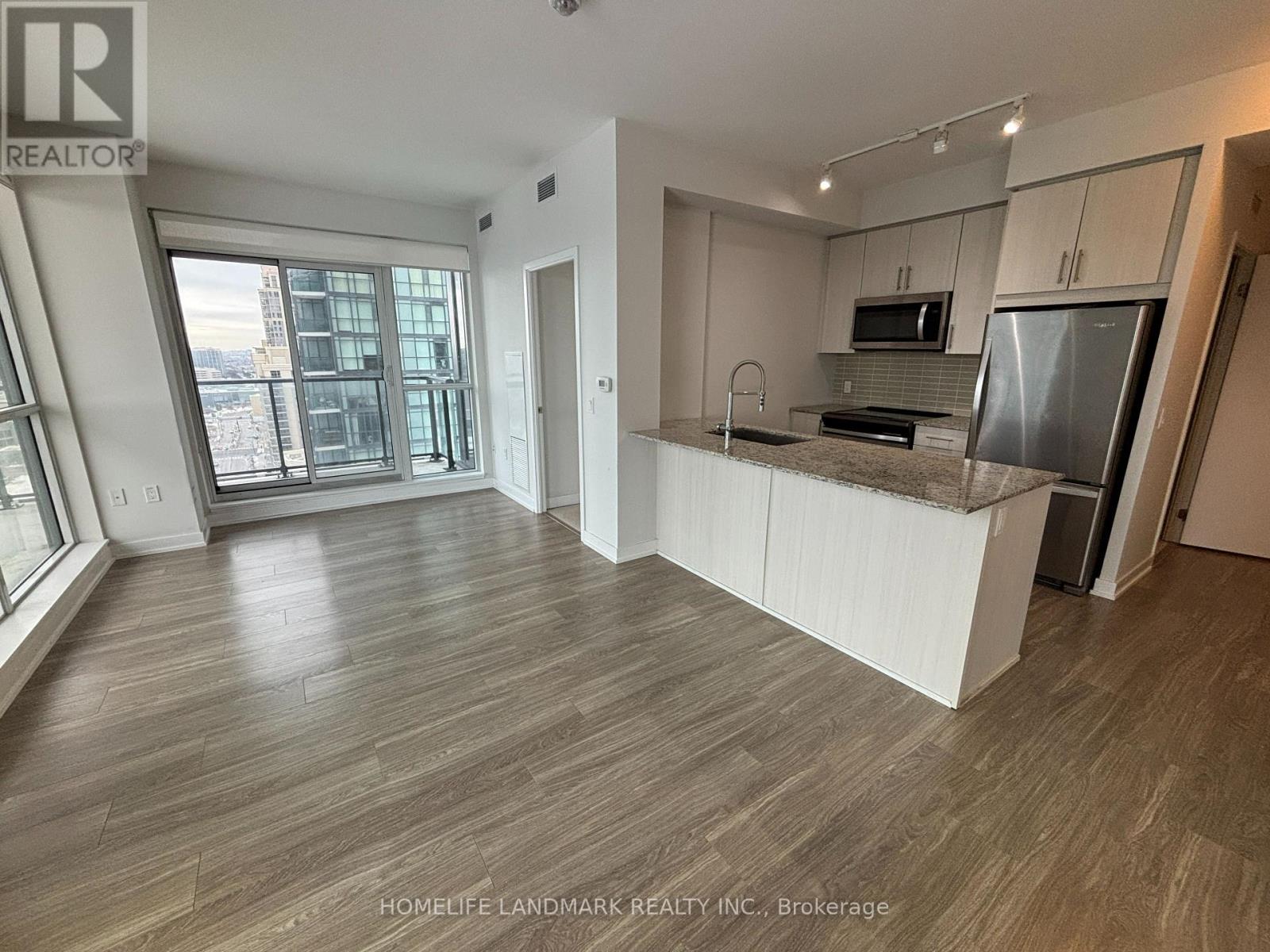 A spacious kitchen with a refrigerator, microwave, and oven.