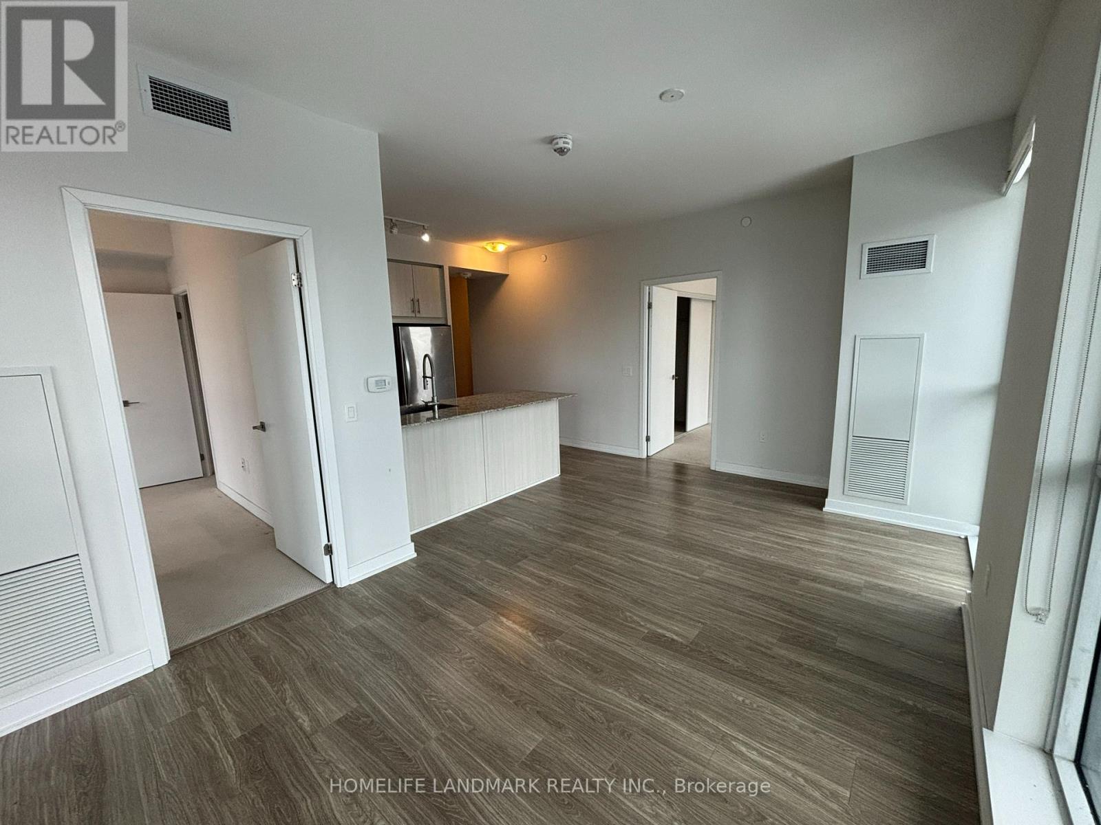 A spacious room with wooden flooring and white walls.